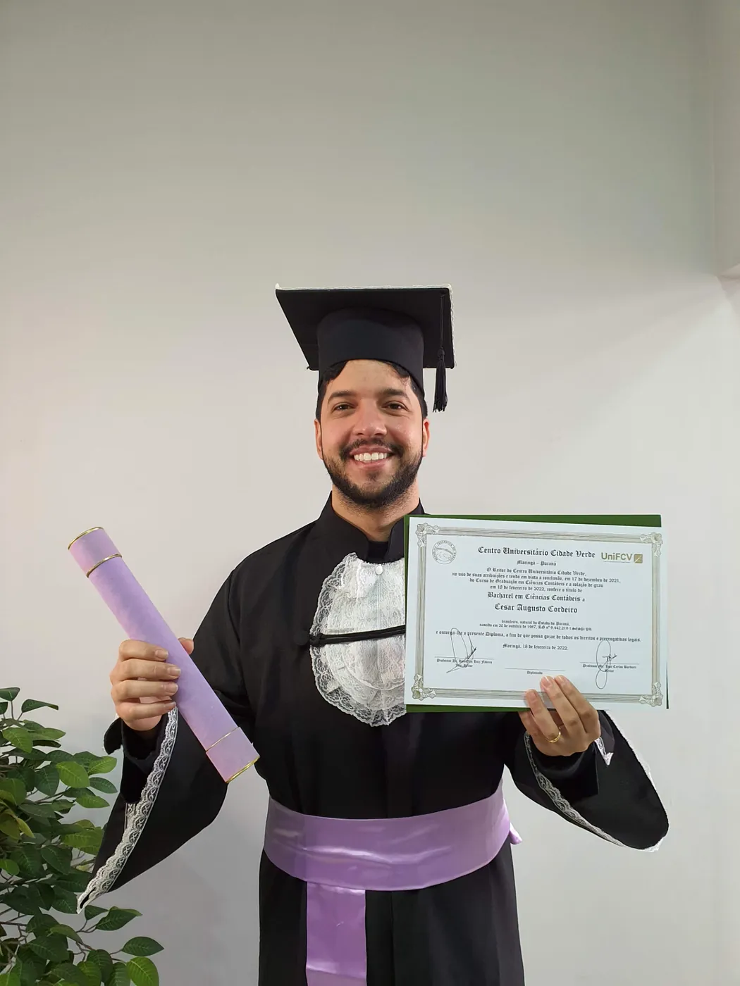 Formando exibindo o diploma de bacharel recebido na colação de grau
